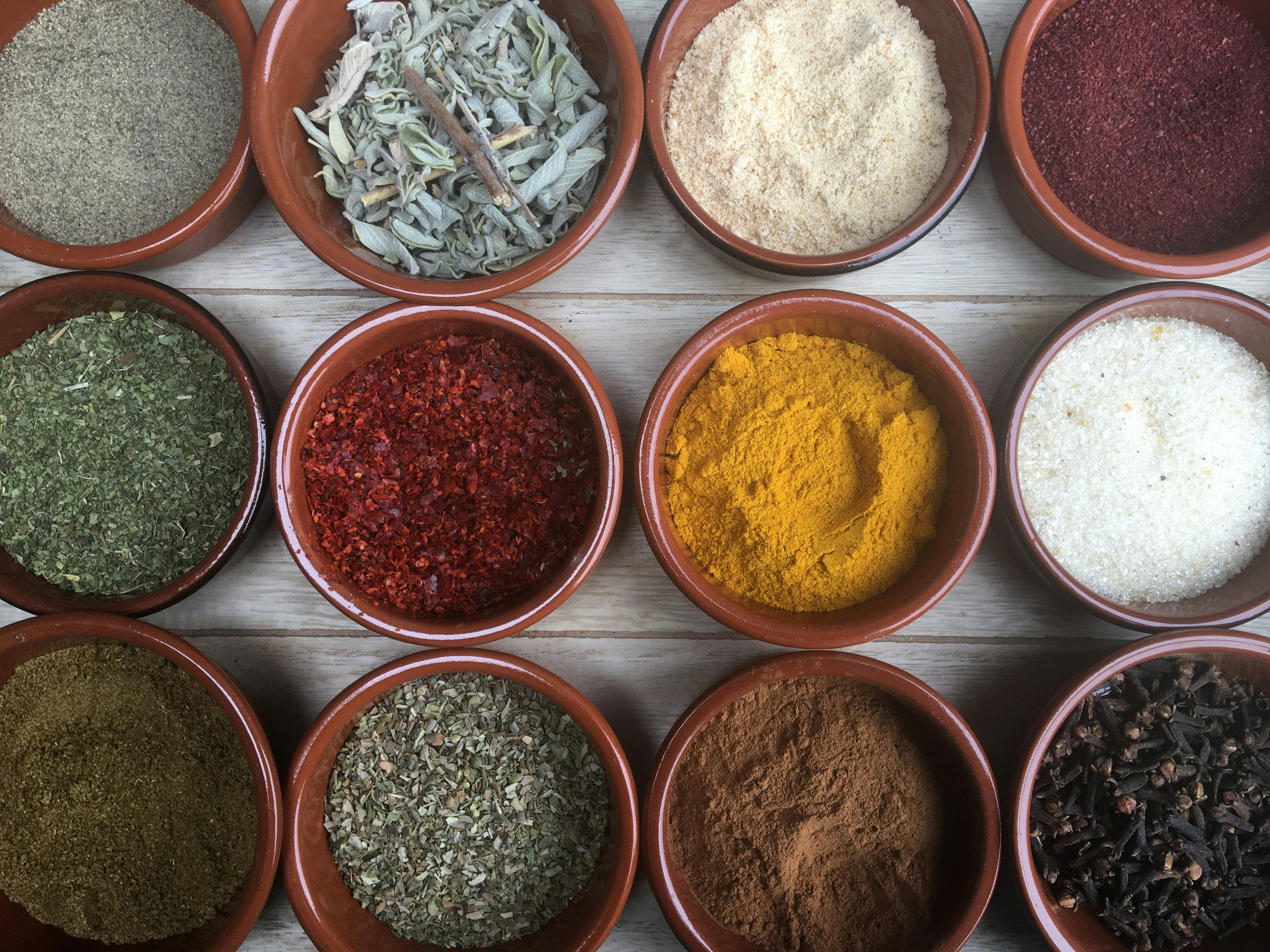 Assorted spices in small bowls on a wooden surface